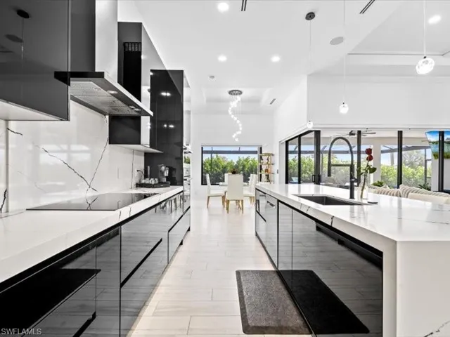 Kitchen featuring modern cabinets, hanging light fixtures, light stone counters, black electric cooktop, and a spacious island