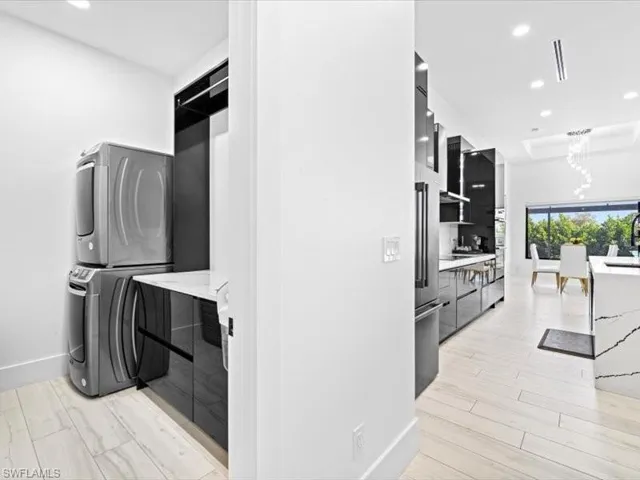 Laundry area with recessed lighting, stacked washer / dryer, and light wood-style flooring