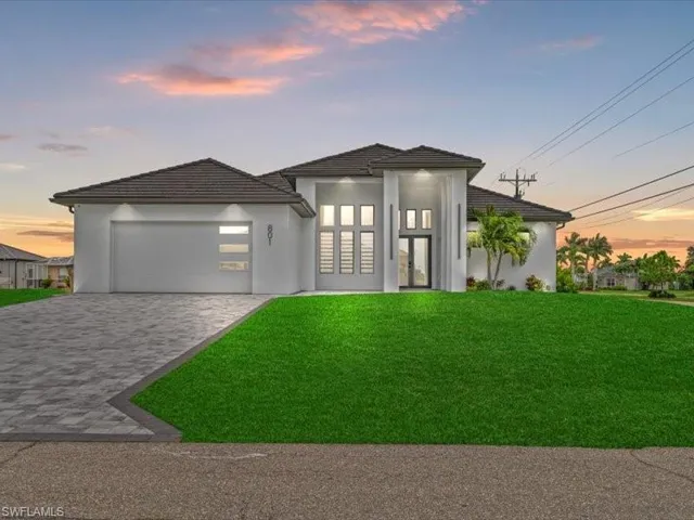 View of front of house featuring a front lawn, decorative driveway, stucco siding, and an attached garage