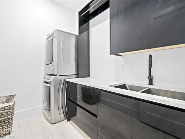 Laundry area featuring stacked washer / drying machine and cabinet space