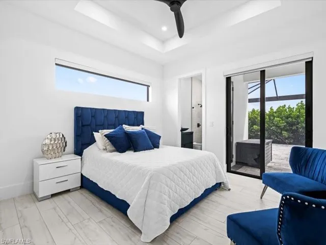 Bedroom featuring access to outside, ceiling fan, wood finished floors, a tray ceiling, and recessed lighting