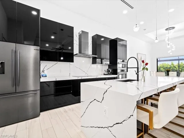 Kitchen featuring a kitchen bar, stainless steel appliances, dark cabinets, modern cabinets, and decorative light fixtures