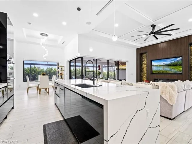 Kitchen featuring modern cabinets, white cabinets, light stone counters, coffered ceiling, and healthy amount of natural light