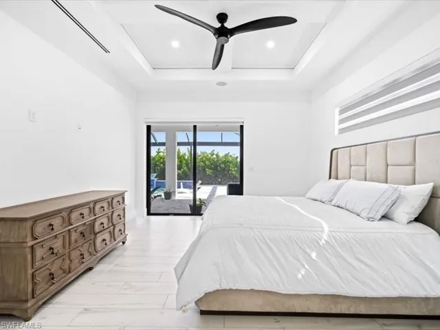 Bedroom with access to outside, ceiling fan, a raised ceiling, and recessed lighting