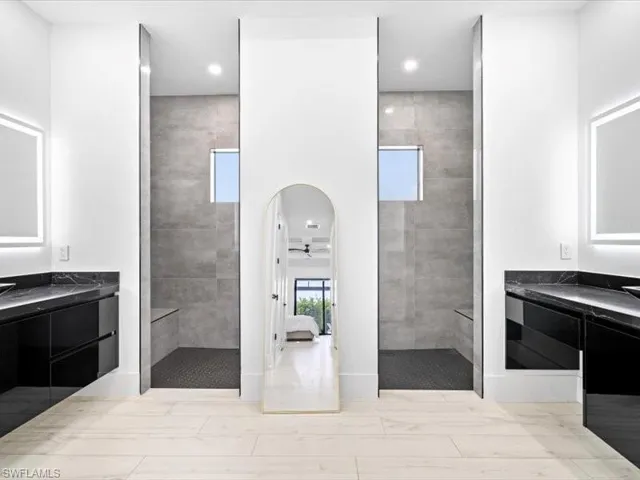Full bathroom featuring a walk in shower, two vanities, and recessed lighting