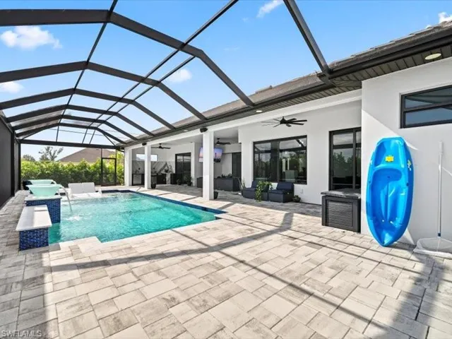 Outdoor pool featuring a sunroom, glass enclosure, and a patio area