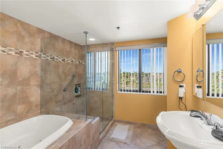 Full bath with baseboards, a tub with jets, tile patterned flooring, a shower stall, and a sink