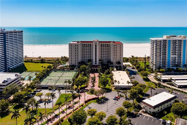 Birds eye view of property with a water view and a beach view