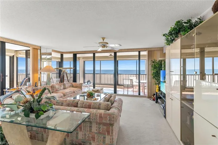 Living area featuring expansive windows, a ceiling fan, a textured ceiling, and light colored carpet