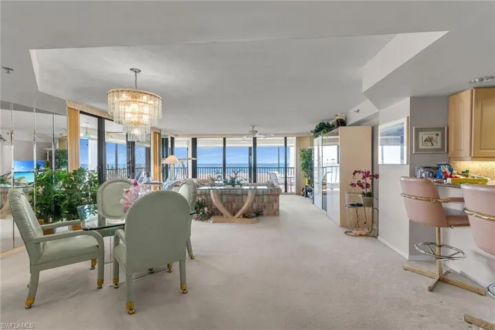 Dining space with baseboards, a wall of windows, carpet flooring, and a notable chandelier