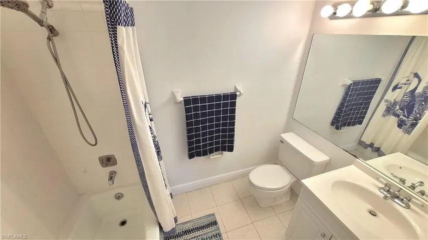 Bathroom featuring shower / bath combination with curtain, vanity, and light tile patterned floors