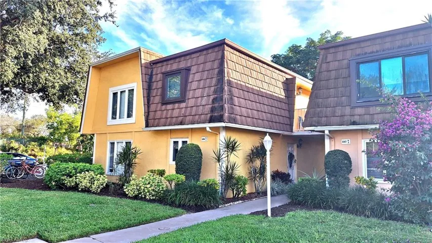 View of front of property featuring mansard roof, stucco siding, and a front yard