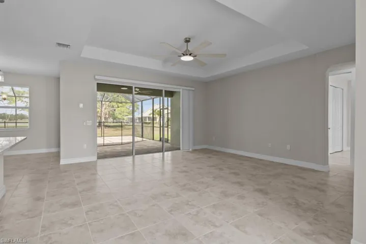Unfurnished room featuring a tray ceiling, a ceiling fan, and light tile patterned floors
