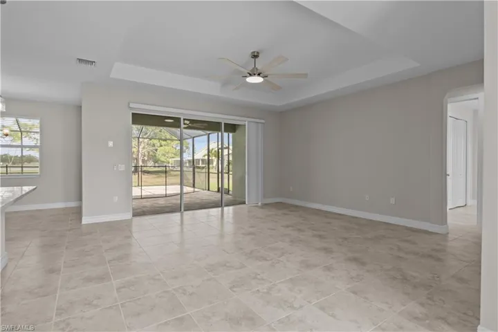 Empty room featuring ceiling fan, a raised ceiling, and light tile patterned floors
