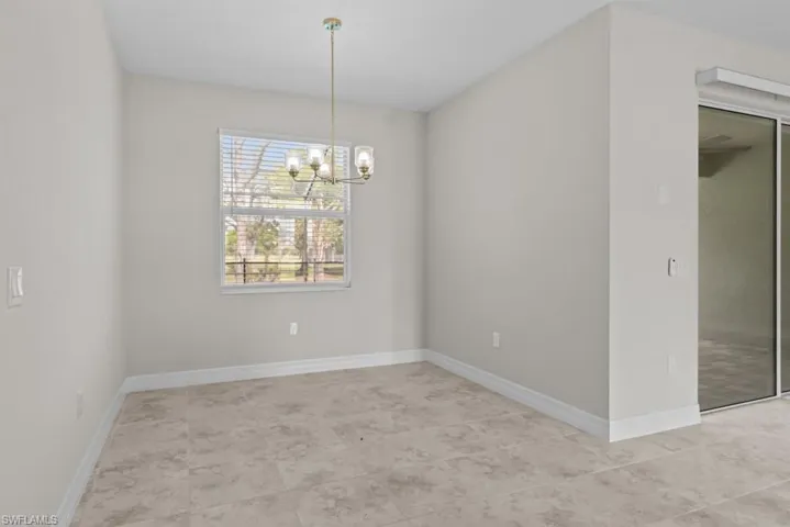 Unfurnished dining area with a chandelier and baseboards