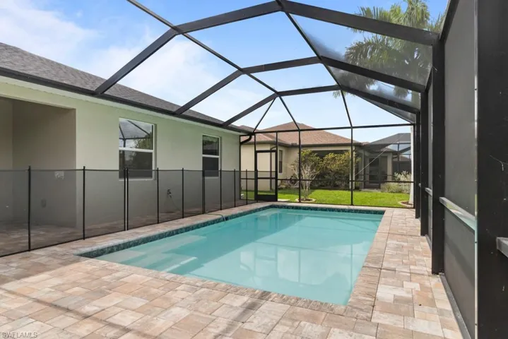 Outdoor pool featuring a sunroom, a patio area, a lanai, and a lawn