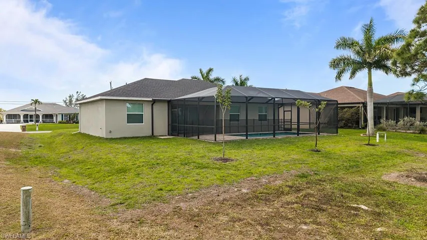 Rear view of house featuring a sunroom, a yard, glass enclosure, an outdoor pool, and a patio