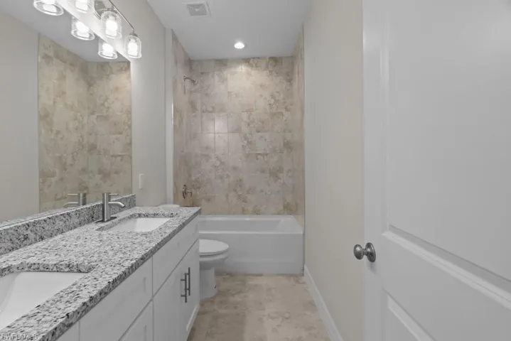 Full bath with double vanity, shower / washtub combination, and recessed lighting