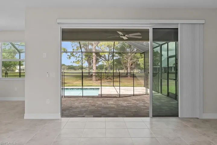 Doorway to outside featuring ceiling fan, a sunroom, and tile patterned flooring