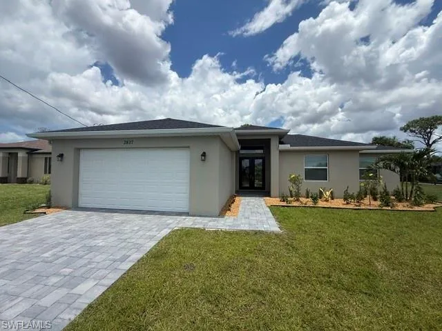 Contemporary stucco exterior featuring a two-car garage, paver driveway, and a covered entry with double front doors