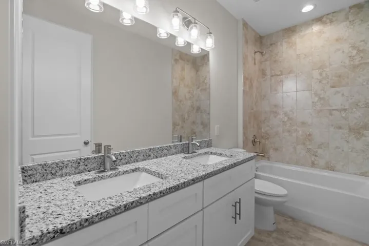 Full bath with double vanity, shower / washtub combination, and recessed lighting