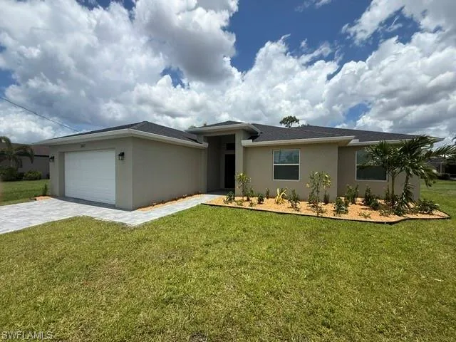 Stucco exterior with a dark shingle roof, paver driveway, and a two-car garage
