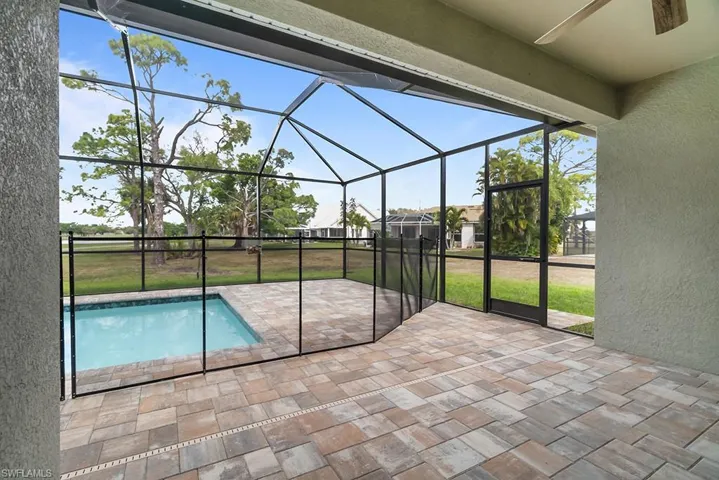 Outdoor pool with a patio area, glass enclosure, a yard, and a sunroom