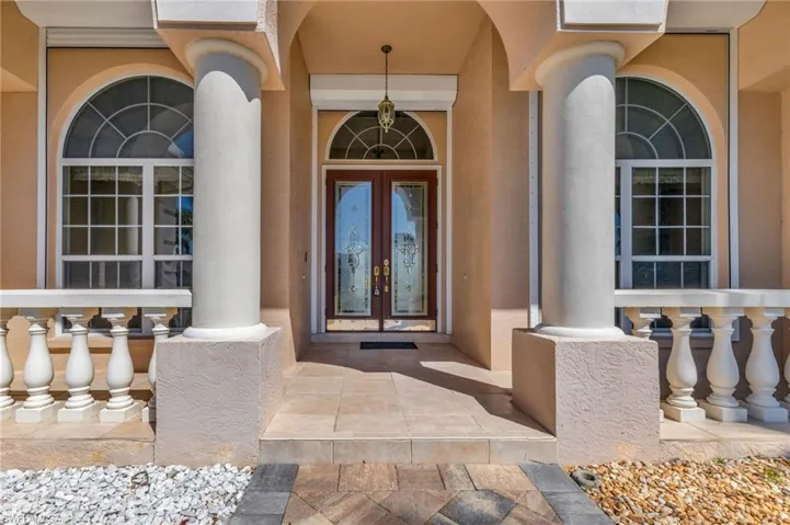 View of exterior entry with stucco siding, a porch, and french doors