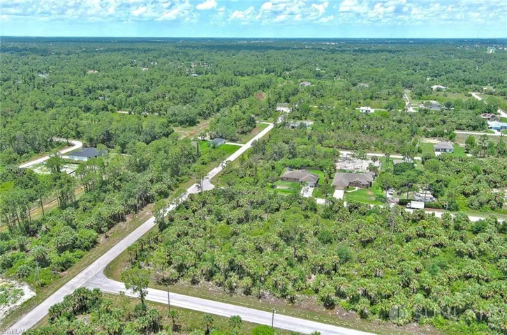Aerial view of property and surrounding area with a heavily wooded area