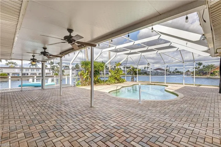 Outdoor pool with a ceiling fan, glass enclosure, and a patio area