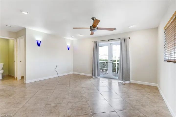 Tiled empty room with plenty of natural light, baseboards, and french doors