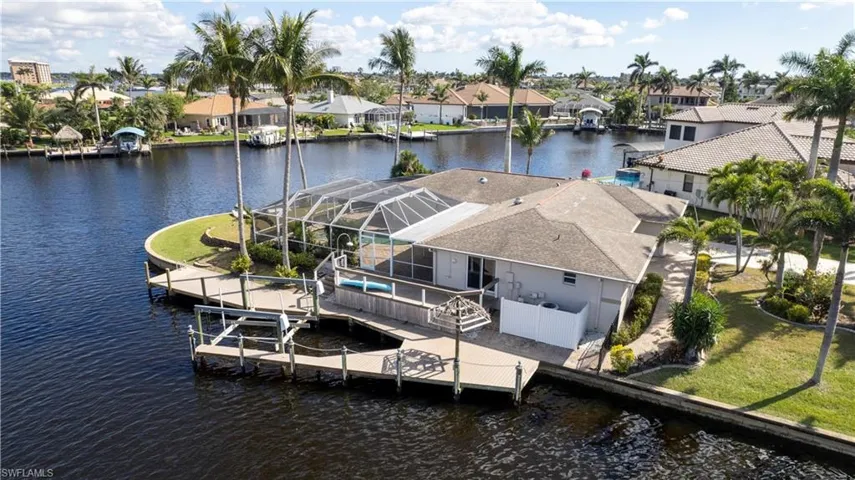 View of dock with a yard, a water view, a lanai, and a residential view