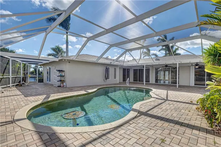Outdoor pool featuring glass enclosure, a patio area, and a ceiling fan