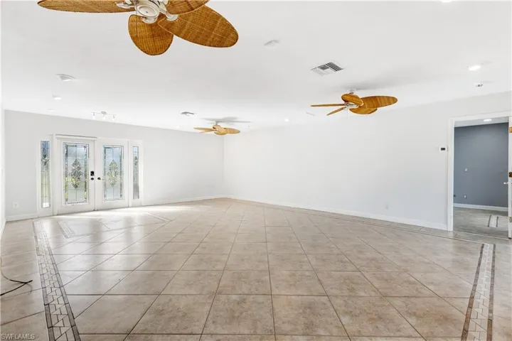 Tiled spare room featuring baseboards, visible vents, ceiling fan, and french doors
