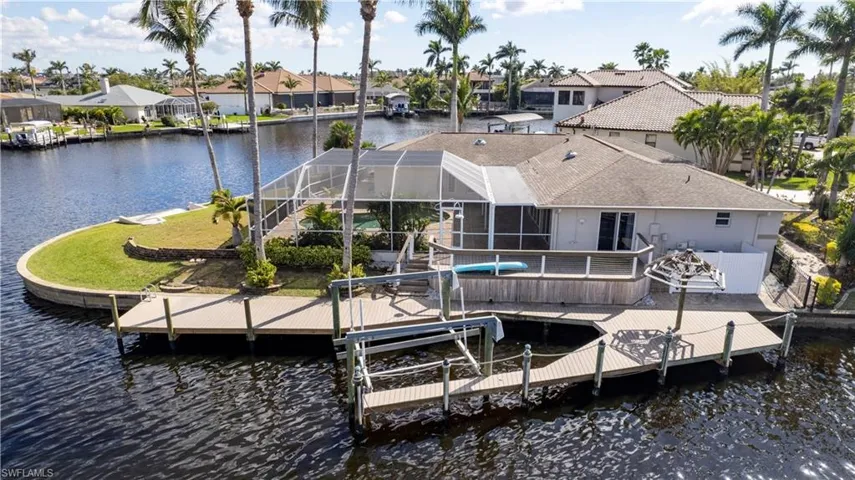 View of dock featuring boat lift, a pool, a water view, glass enclosure, and a residential view
