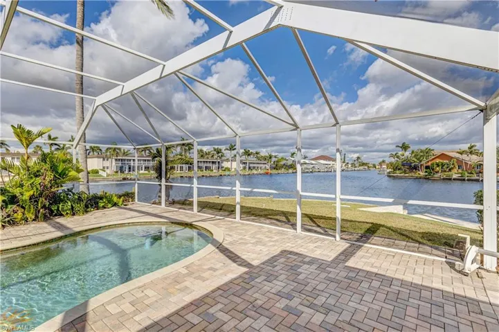 Pool with a patio area, glass enclosure, and a water view