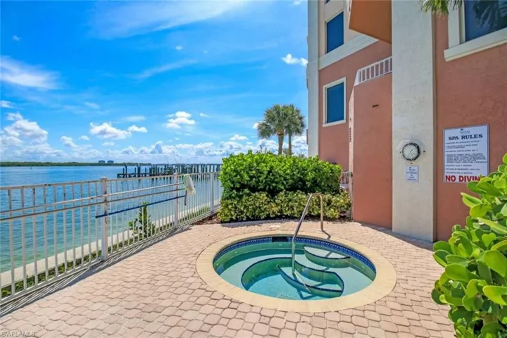View of pool featuring a water view, a hot tub, and a patio