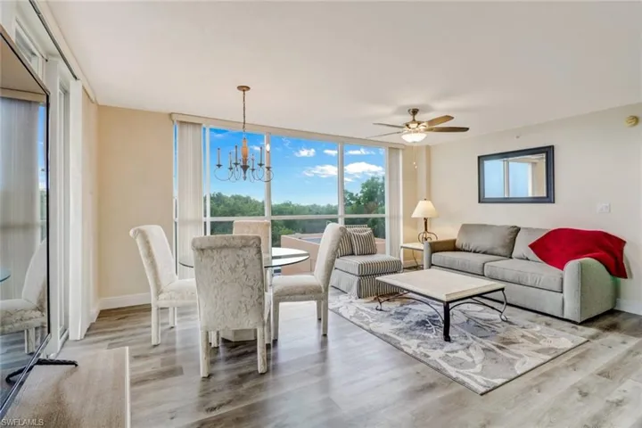 Living room with a chandelier, light wood-style flooring, a ceiling fan, and expansive windows