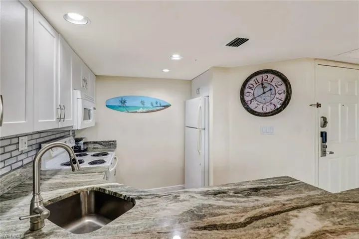 Kitchen featuring white cabinetry, white appliances, light stone countertops, tasteful backsplash, and recessed lighting