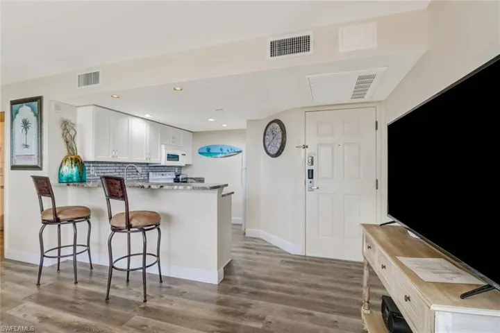 Kitchen featuring white cabinetry, a breakfast bar, backsplash, recessed lighting, and light wood finished floors