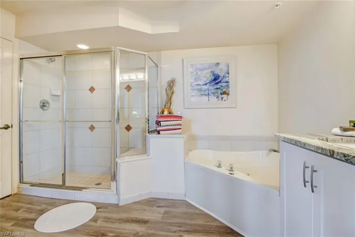 Full bath with light wood-type flooring, vanity, a bath, and a shower stall