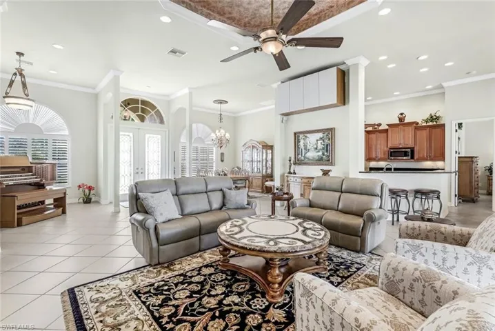 Great Room with crown molding, light tile patterned floors, and ceiling fan with notable chandelier