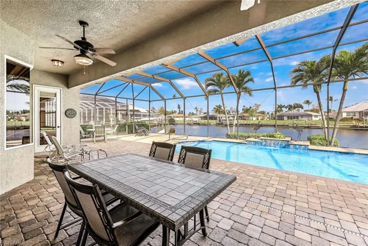 View of pool with a water view, lanai, and ceiling fan