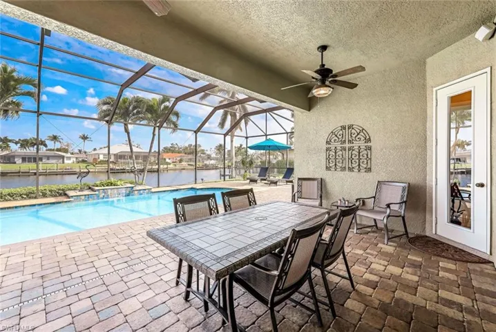 View of swimming pool featuring a water view, lanai, and ceiling fan
