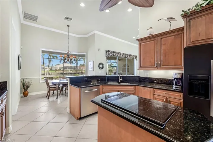 Kitchen featuring black appliances, sink, dark stone counters, pendant lighting, and ornamental molding