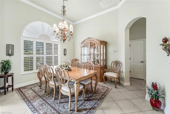 Tiled dining room featuring a notable chandelier, plenty of natural light, and crown molding