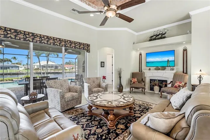 Tiled Great Room featuring ornamental molding, tray ceiling, and ceiling fan facing pristine pool area and almost 200' wide canal