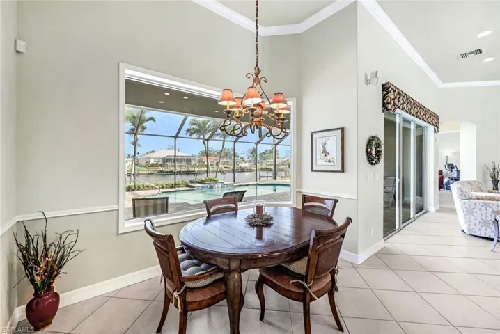 Tiled dining area with a water view, crown molding, and a chandelier