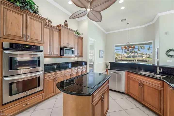 Kitchen featuring light tile patterned flooring, stainless steel appliances, sink, and dark stone counters