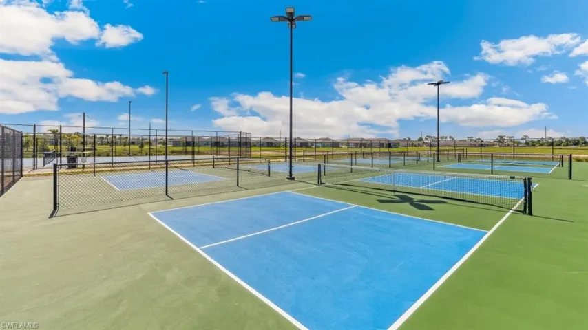 Well-maintained outdoor courts with blue playing surfaces and green surrounds, complete with nets and perimeter fencing